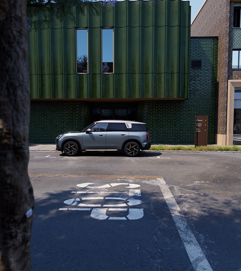 MINI Countryman visto de lado, estacionado numa rua junto a um edifício verde 